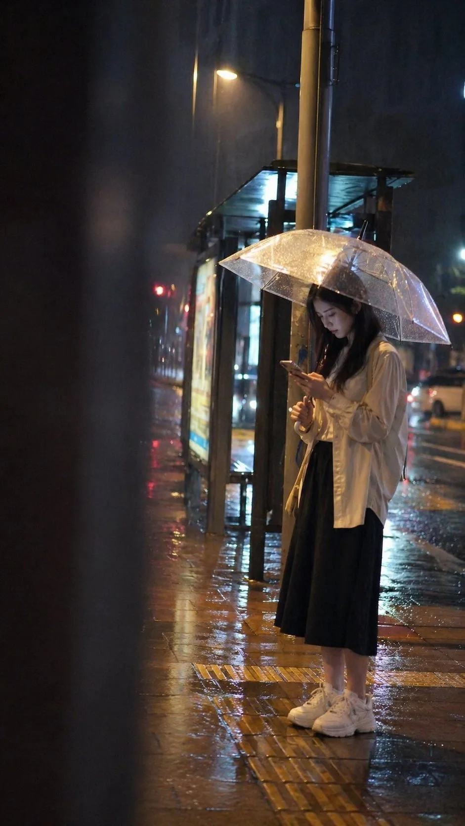 雨夜的城市女性打着雨伞在等公交车